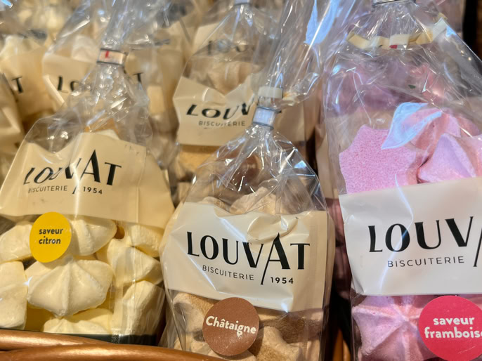 Des sachets de bonbons colorés dans des paniers en osier, avec des étiquettes "LOUVAT".