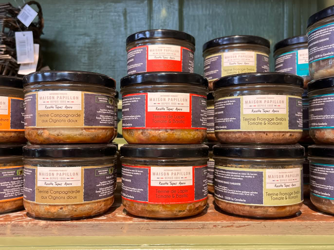 Des pots de condiments colorés empilés sur une étagère en bois.