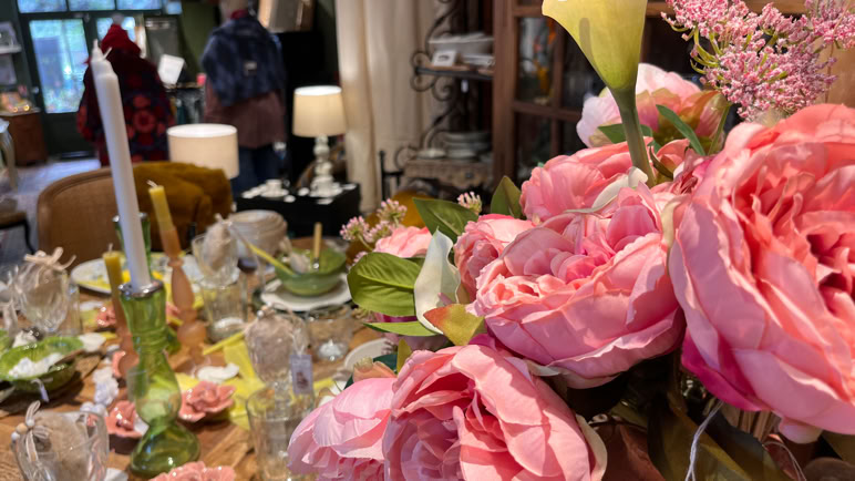 Salon avec deux canapés, une table basse avec des verres et des assiettes, des coussins colorés, et des décorations florales.