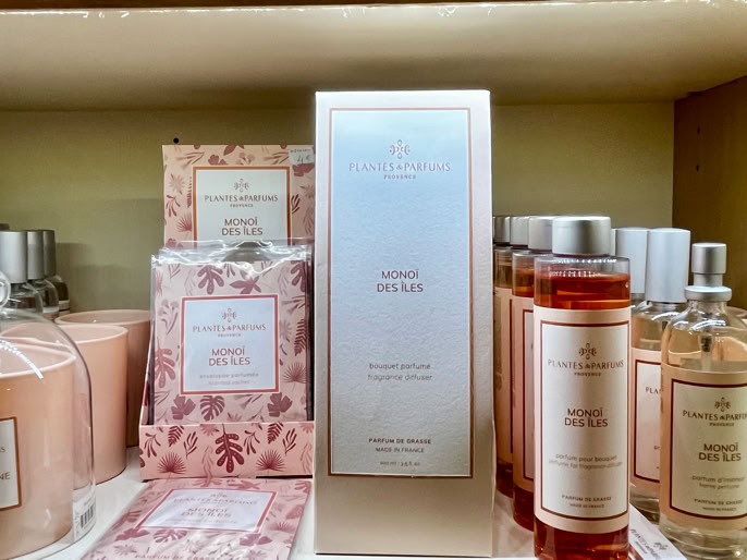 Produits de beauté et parfums disposés sur une étagère, comprenant des bougies, des lotions et des boîtes décoratives.