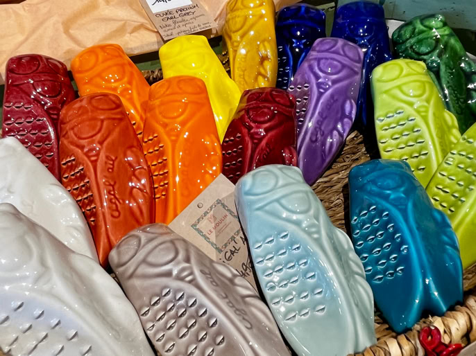 Des savons colorés en forme de chaussures sont disposés dans un panier.