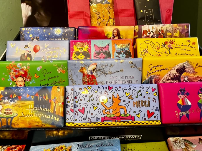 Boîtes de chocolat colorées avec des illustrations variées, disposées sur un présentoir.