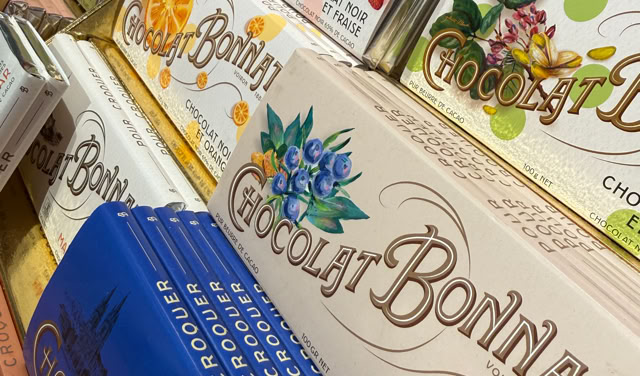 Tablettes de chocolat Bonnat de différentes couleurs et saveurs empilées sur une étagère.