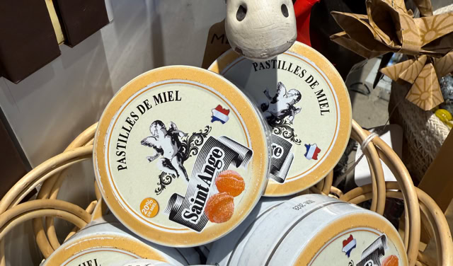 Panier contenant plusieurs boîtes rondes avec l'inscription "Pastilles de Miel" et une illustration d'un âne, avec une peluche d'âne en arrière-plan.