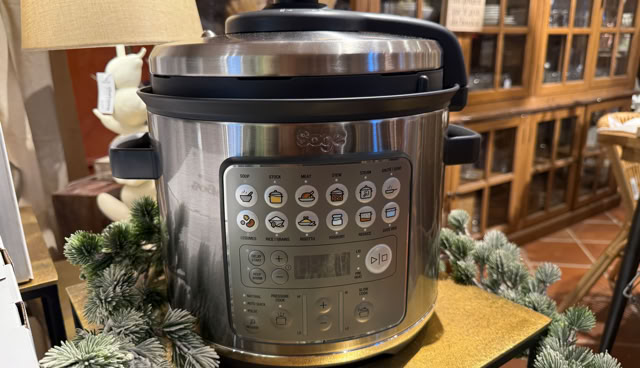 Boîtes de petits électroménagers de la marque Sage empilées sur des tables, avec un grille-pain en métal au premier plan.