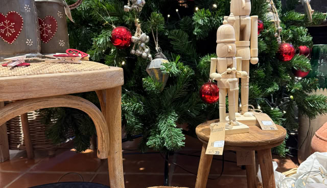 Décoration de Noël avec un sapin orné de boules rouges et blanches, des objets en bois sur un tabouret, et divers articles disposés autour.