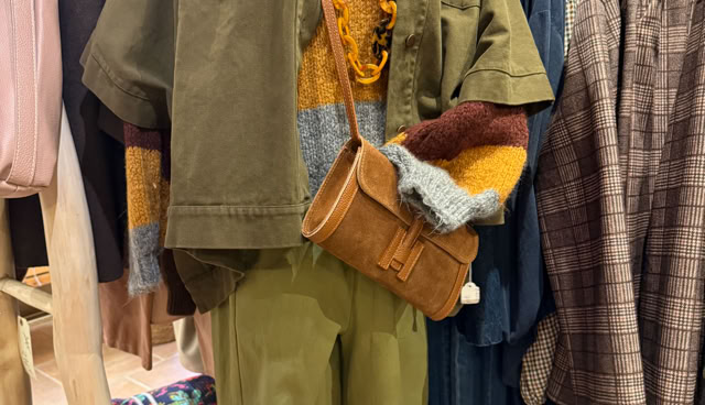 Mannequin portant une tenue composée d'une veste kaki, d'un pull multicolore, d'un pantalon vert, d'un collier jaune et d'un sac marron.