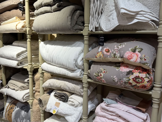 Étagère remplie de couvertures et de plaids pliés de différentes couleurs et motifs.