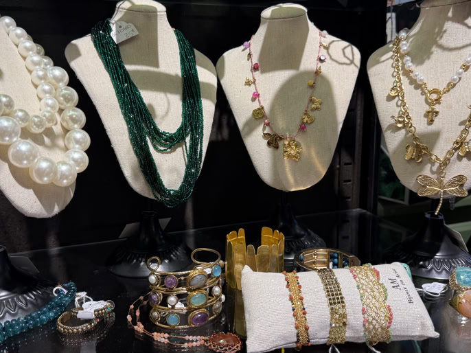 Présentoir avec divers colliers, bracelets et bijoux sur des bustes et un coussin.